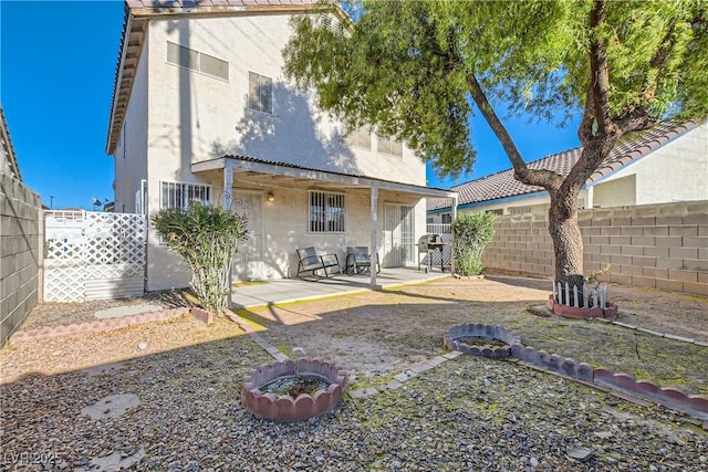 back of property featuring a fire pit and a patio