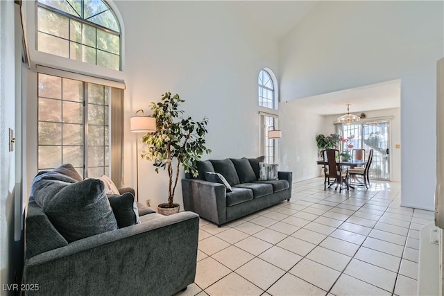 living room with a notable chandelier, a towering ceiling, and light tile patterned flooring