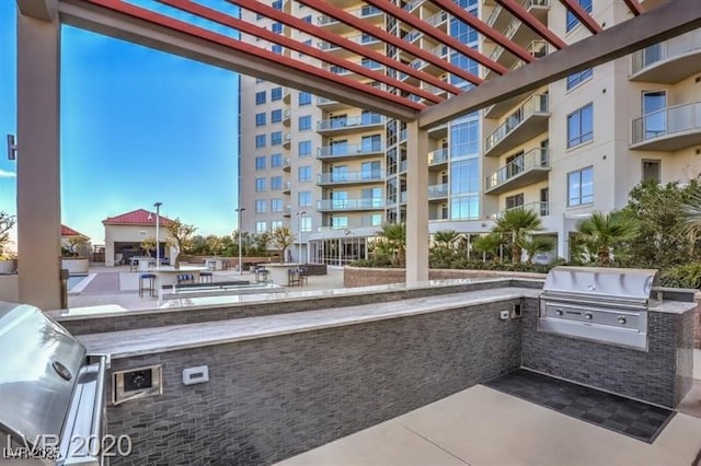 exterior space with an outdoor kitchen, a pergola, and grilling area