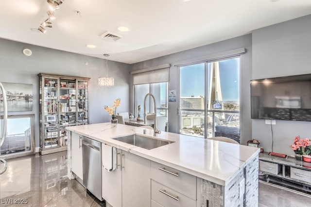 kitchen with a center island with sink, stainless steel dishwasher, white cabinets, light stone counters, and sink