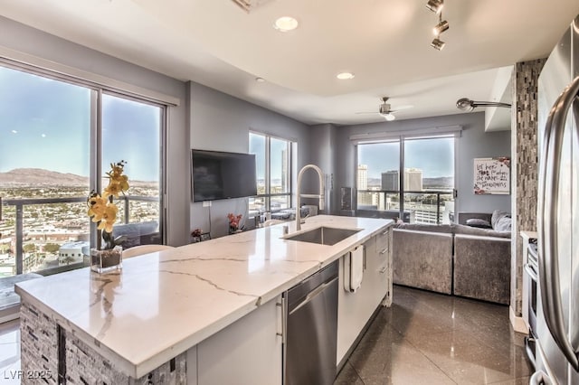 kitchen with ceiling fan, sink, white cabinetry, an island with sink, and stainless steel appliances