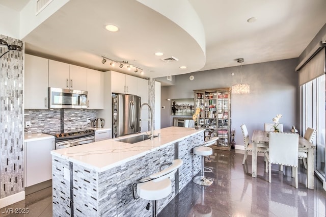 kitchen featuring white cabinets, a kitchen island with sink, appliances with stainless steel finishes, and pendant lighting