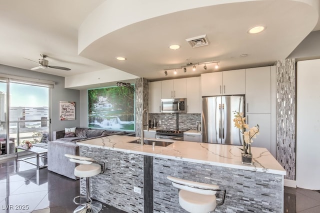 kitchen with tasteful backsplash, sink, light stone countertops, stainless steel appliances, and white cabinets