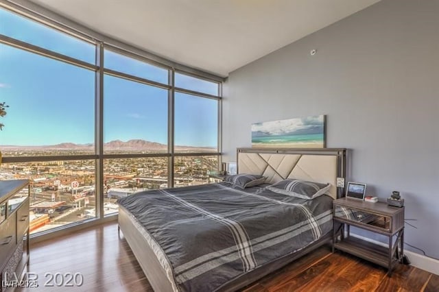 bedroom featuring a wall of windows, a mountain view, and wood-type flooring