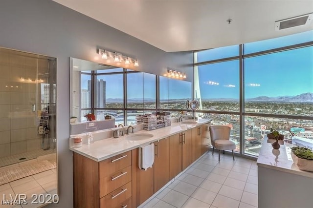 bathroom featuring tile patterned flooring, floor to ceiling windows, a shower with shower door, and sink