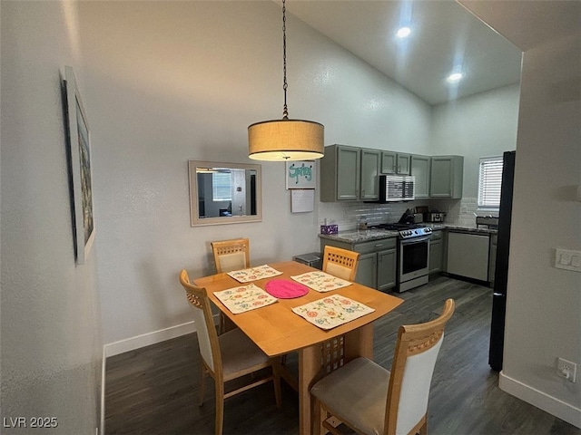 kitchen with tasteful backsplash, high vaulted ceiling, stainless steel range oven, dark hardwood / wood-style floors, and hanging light fixtures