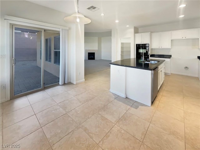 kitchen featuring sink, light tile patterned floors, stainless steel dishwasher, a center island with sink, and white cabinets