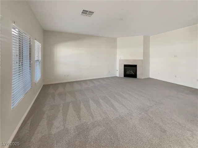 unfurnished living room with carpet and a tiled fireplace