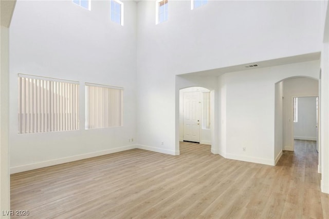 empty room featuring a high ceiling and light hardwood / wood-style flooring