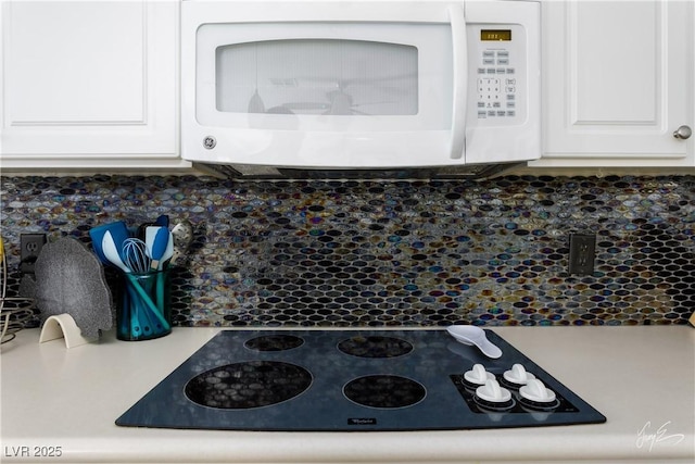 details with black electric stovetop, white cabinetry, and decorative backsplash