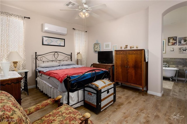 bedroom with ceiling fan, light hardwood / wood-style floors, and an AC wall unit