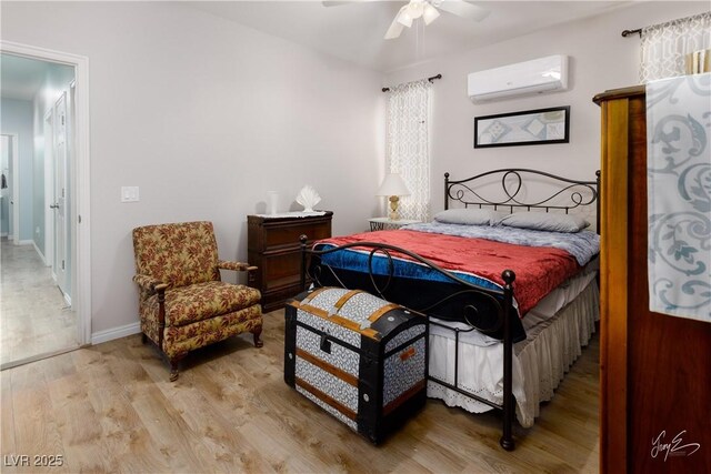 bedroom with baseboards, a wall mounted AC, light wood-style flooring, and ceiling fan