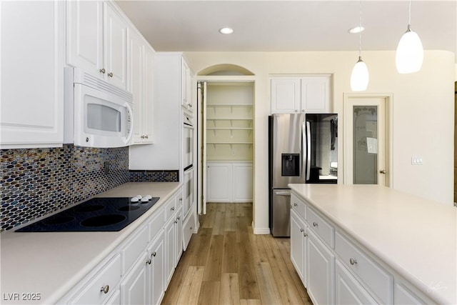 206 Pebble Creek Hts, Mesquite, NV 89027 - kitchen with white microwave, stainless steel fridge, black electric cooktop, light wood finished floors, and white cabinetry