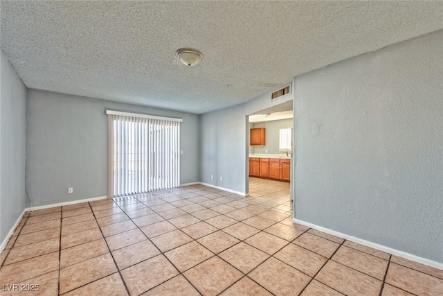 spare room with plenty of natural light, light tile patterned floors, and a textured ceiling