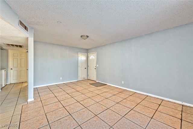 empty room featuring light tile patterned floors and a textured ceiling