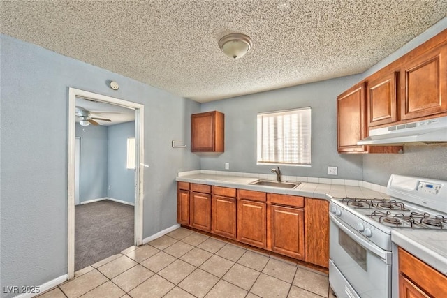 kitchen featuring white gas range oven, a textured ceiling, ceiling fan, sink, and light tile patterned flooring