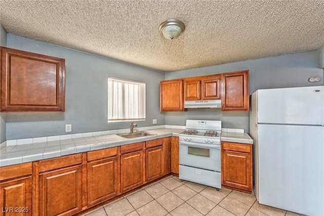 kitchen with tile counters, sink, a textured ceiling, white appliances, and light tile patterned flooring