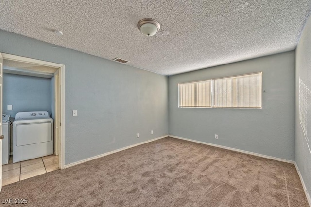 unfurnished room featuring light carpet, a textured ceiling, and washing machine and clothes dryer