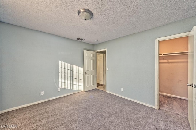 unfurnished bedroom featuring a spacious closet, carpet floors, a textured ceiling, and a closet