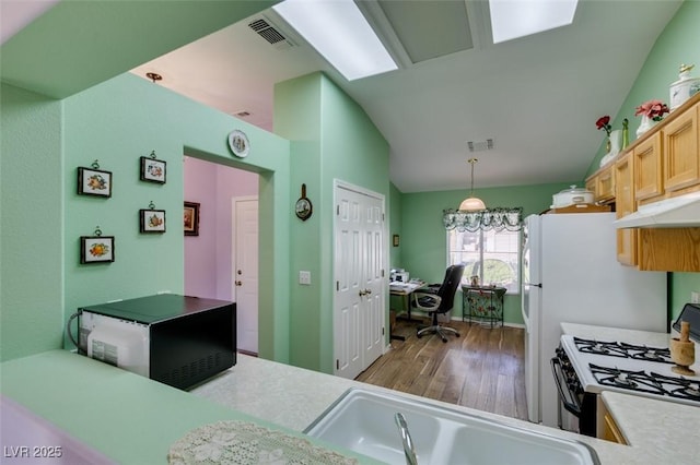 kitchen featuring lofted ceiling, light brown cabinets, pendant lighting, and black gas stove