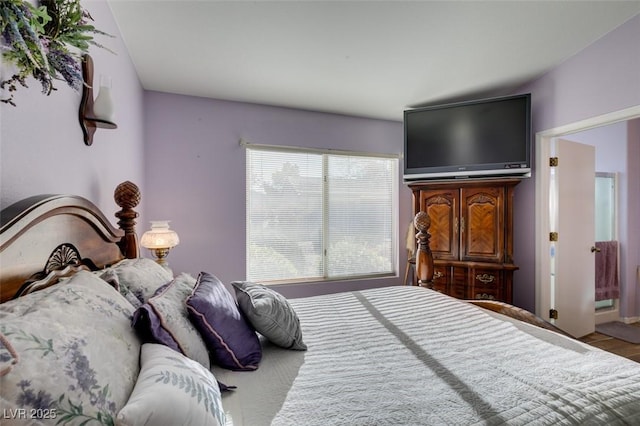 bedroom with ensuite bathroom and hardwood / wood-style flooring