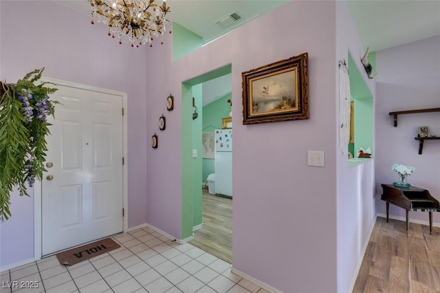 tiled entrance foyer featuring a notable chandelier