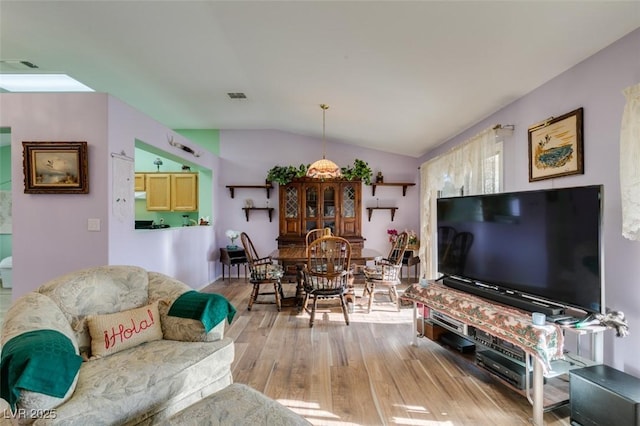 living room with vaulted ceiling and light hardwood / wood-style floors