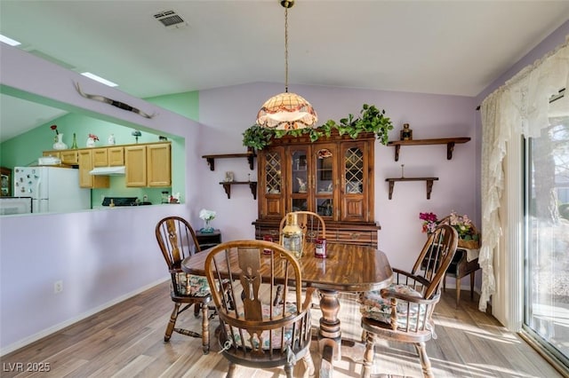 dining area featuring lofted ceiling and light hardwood / wood-style floors