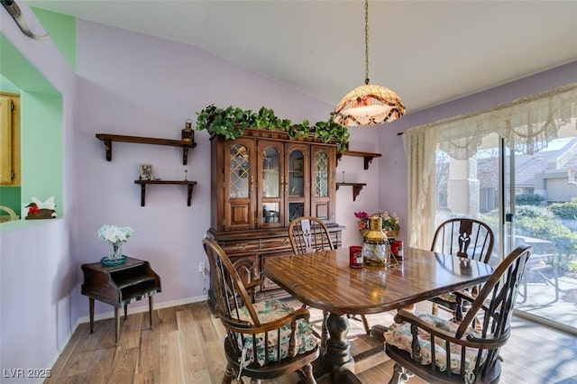 dining room with vaulted ceiling and light hardwood / wood-style flooring