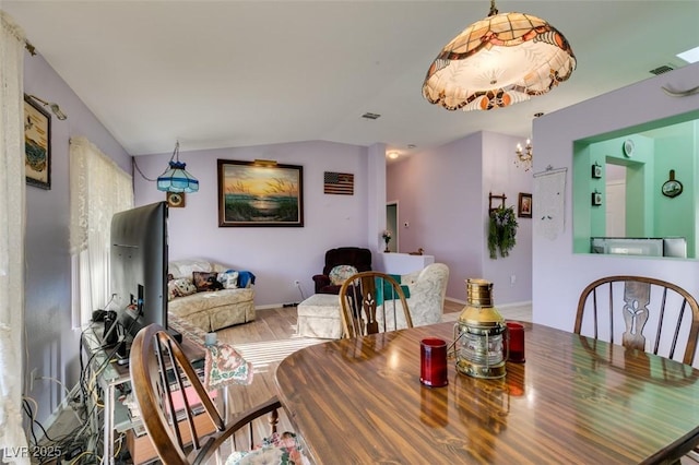 dining area with a notable chandelier, lofted ceiling, and wood-type flooring