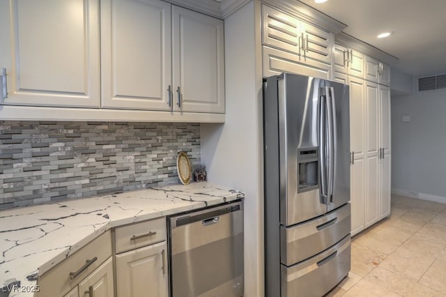 kitchen featuring light tile patterned floors, appliances with stainless steel finishes, backsplash, and light stone countertops