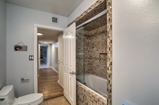 bathroom featuring toilet, tile patterned floors, and shower / bath combination with glass door