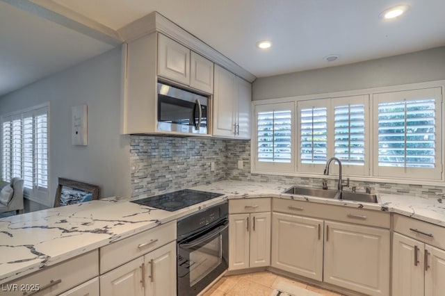 kitchen with light stone countertops, black appliances, decorative backsplash, sink, and light tile patterned flooring