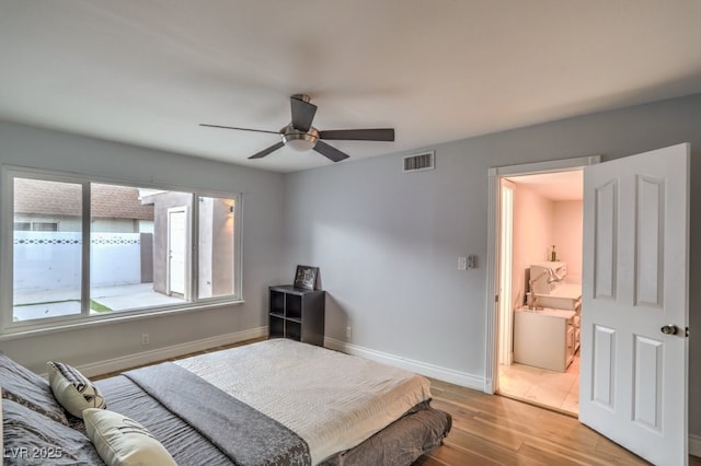 bedroom with light wood-type flooring, ceiling fan, and connected bathroom