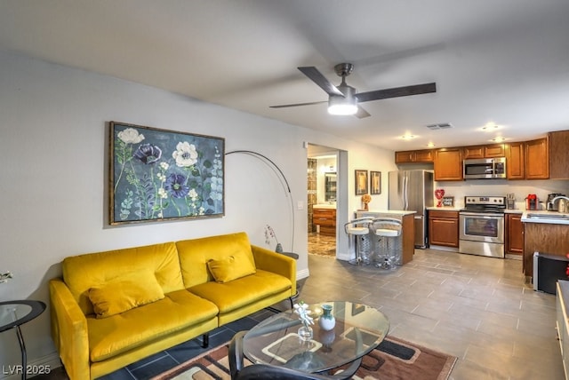 tiled living room featuring ceiling fan and sink