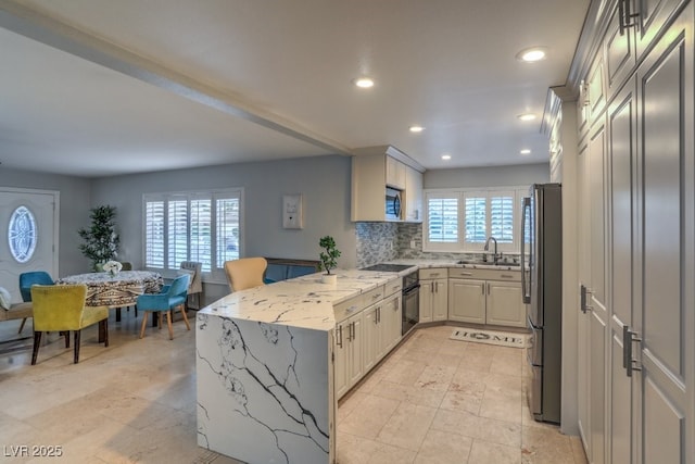 kitchen featuring backsplash, sink, a healthy amount of sunlight, stainless steel appliances, and light stone counters