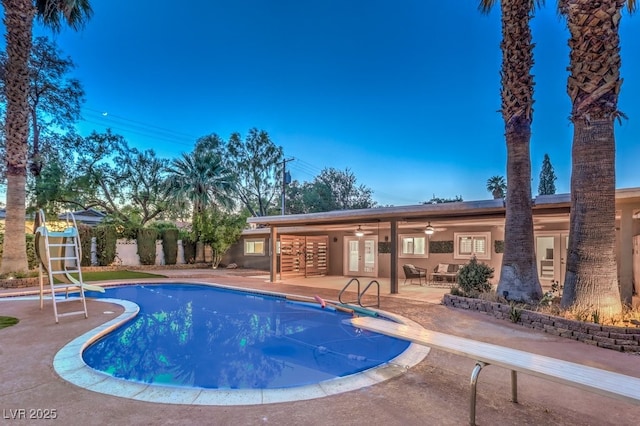 view of pool with a diving board, ceiling fan, and a patio