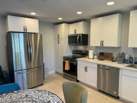 kitchen featuring sink, white cabinetry, light tile patterned floors, and stainless steel appliances