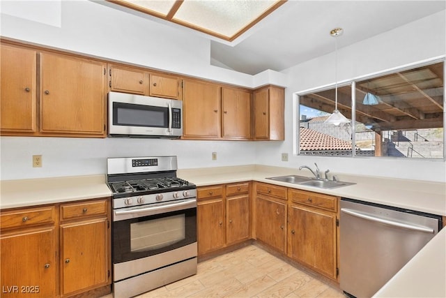 kitchen featuring vaulted ceiling, appliances with stainless steel finishes, light hardwood / wood-style flooring, and sink