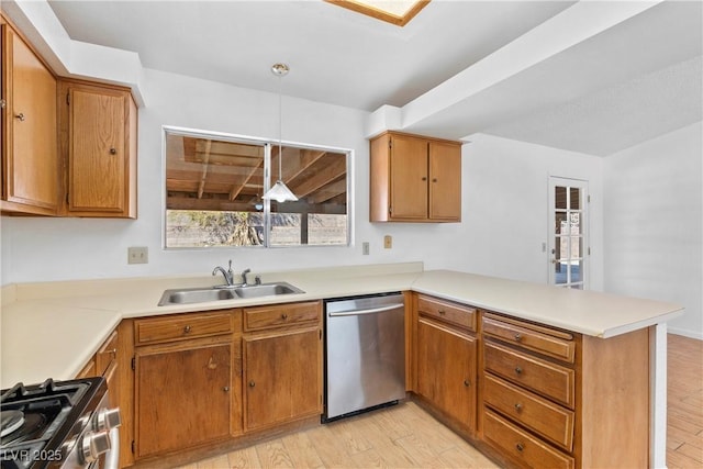 kitchen featuring kitchen peninsula, appliances with stainless steel finishes, decorative light fixtures, light wood-type flooring, and sink