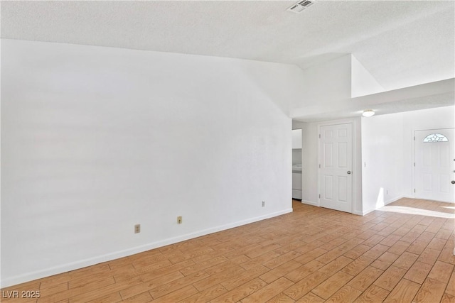 spare room with lofted ceiling, washer / dryer, and light hardwood / wood-style flooring