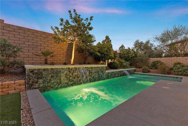 pool at dusk featuring pool water feature