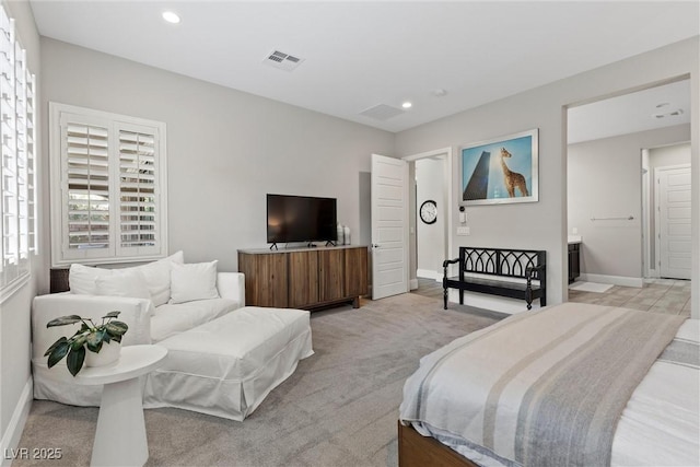 bedroom with light colored carpet and connected bathroom