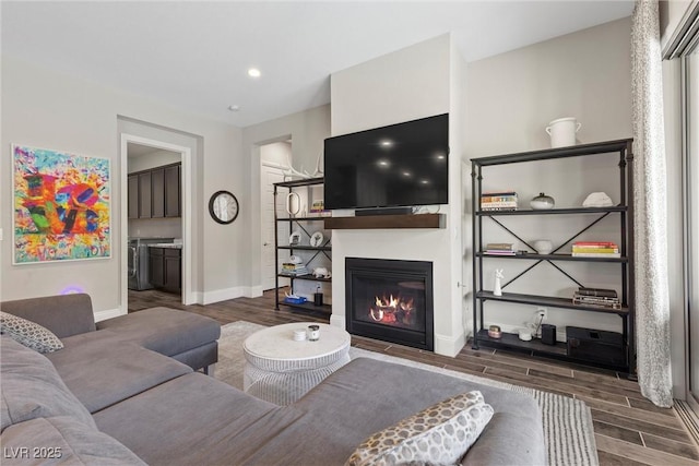 living room with washing machine and dryer and dark hardwood / wood-style flooring