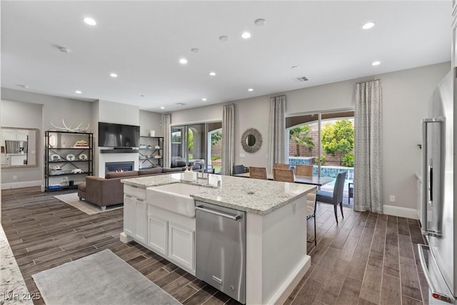 kitchen featuring light stone countertops, appliances with stainless steel finishes, sink, white cabinetry, and an island with sink