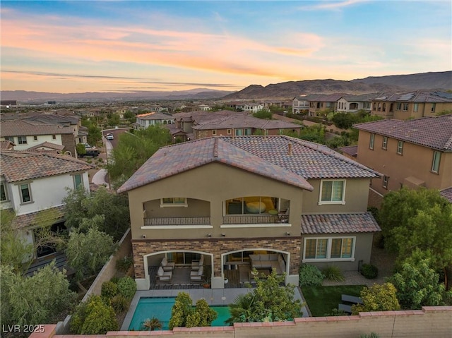 back house at dusk featuring a mountain view, a patio, and a balcony