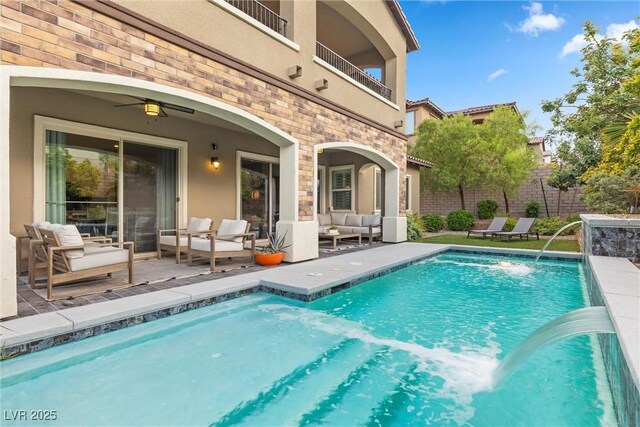 view of pool with pool water feature, ceiling fan, outdoor lounge area, and a patio