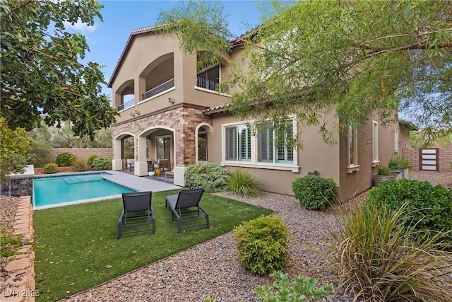 back of house with a lawn, a fenced in pool, and a balcony