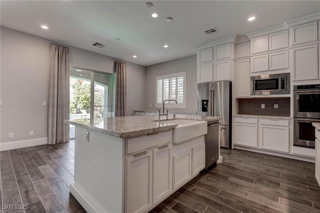 kitchen featuring stainless steel appliances, a sink, dark wood-style flooring, visible vents, and white cabinetry
