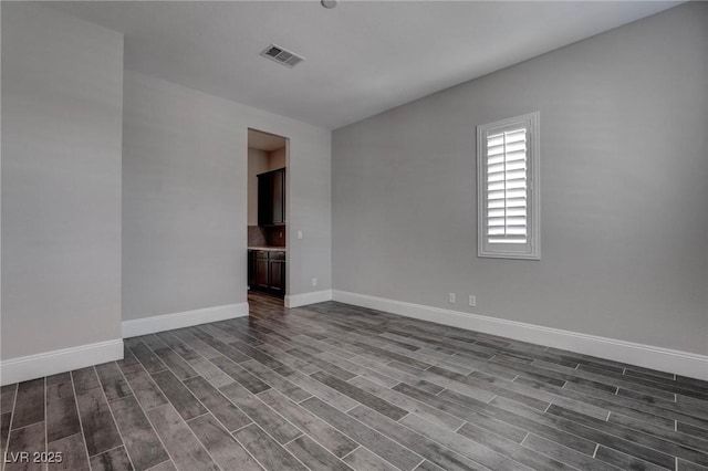 unfurnished room with baseboards, visible vents, and dark wood finished floors